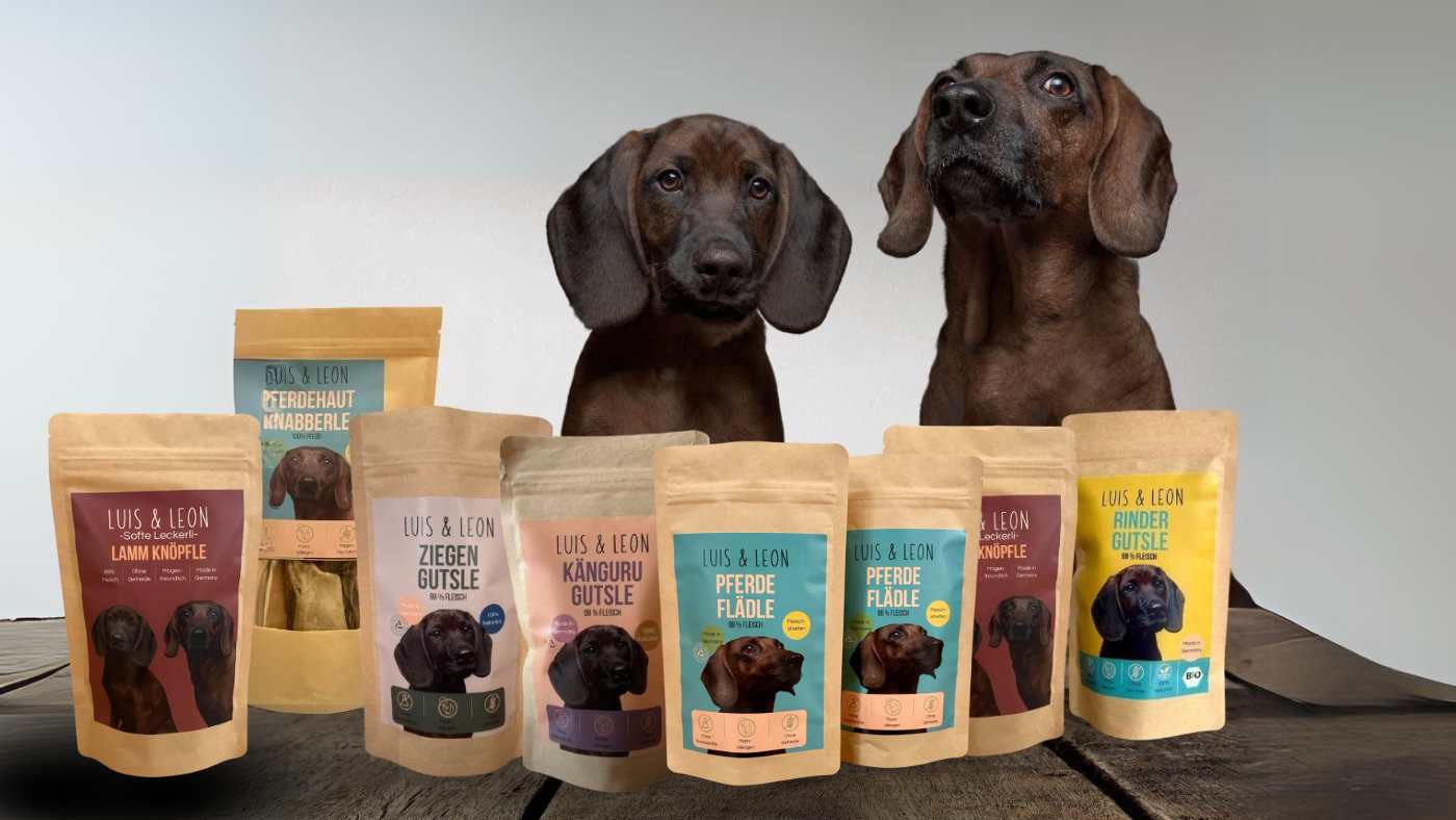 zwei Hunde sitzen vor Leckerli Beuteln