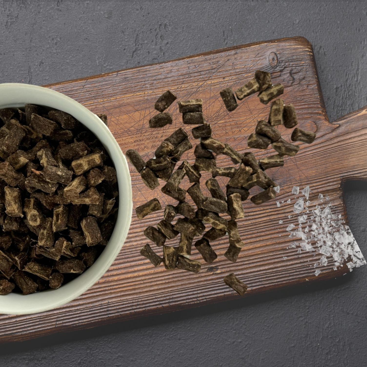 Luis & Leon Gutsle Hundeleckerli auf Holzbrett, daneben weiße Schale gefüllt mit Gutsle